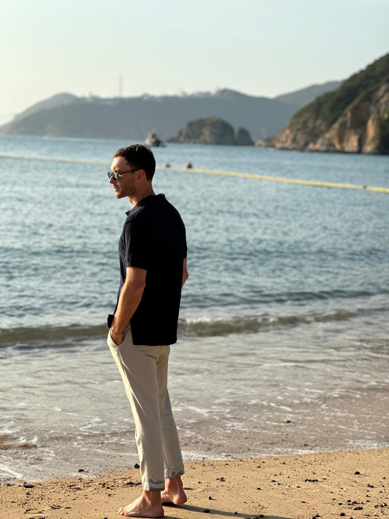 Model wearing Navy Blue WearTerry Towel Polo on the beach demonstrating its traditional use case of wearing terry towel clothing at the beach. 